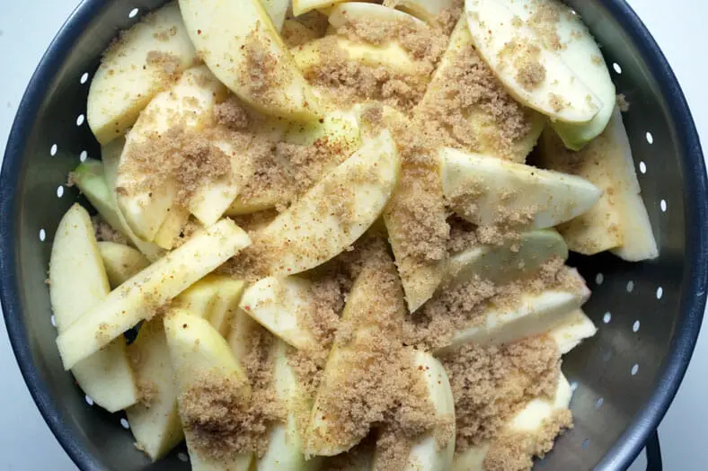 Seasoning apples with sugar and spices for vegan apple pie