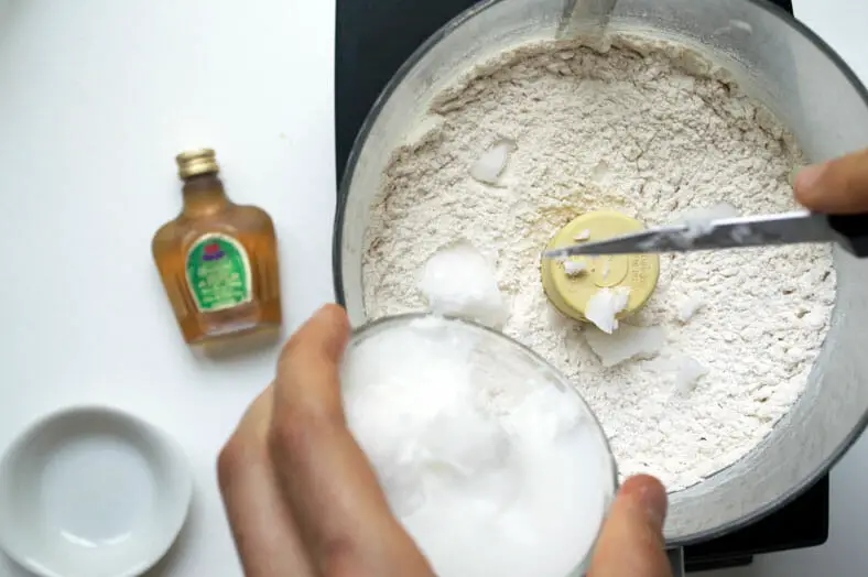 Mixing flour with coconut oil for the dough of a vegan apple pie