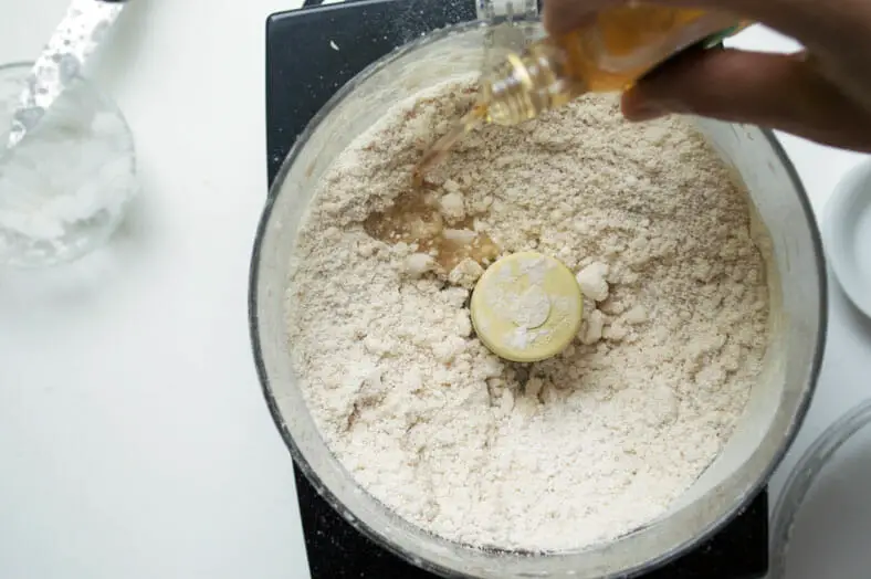Mixing apple liquor with flour and coconut oil for the dough of a vegan apple pie