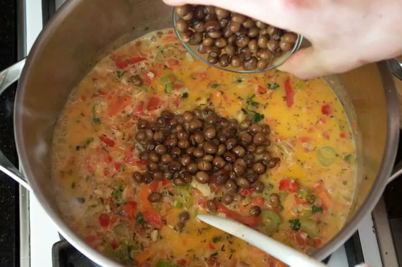 To make Moro de Guandules, a traditional Dominican Pigeon Peas Rice dish, after the vegetables and herbs have simmered together, you'll then add capers and coconut milk - stir everything together and get this beautiful looking stew, in which you will then add rice and pigeon peas