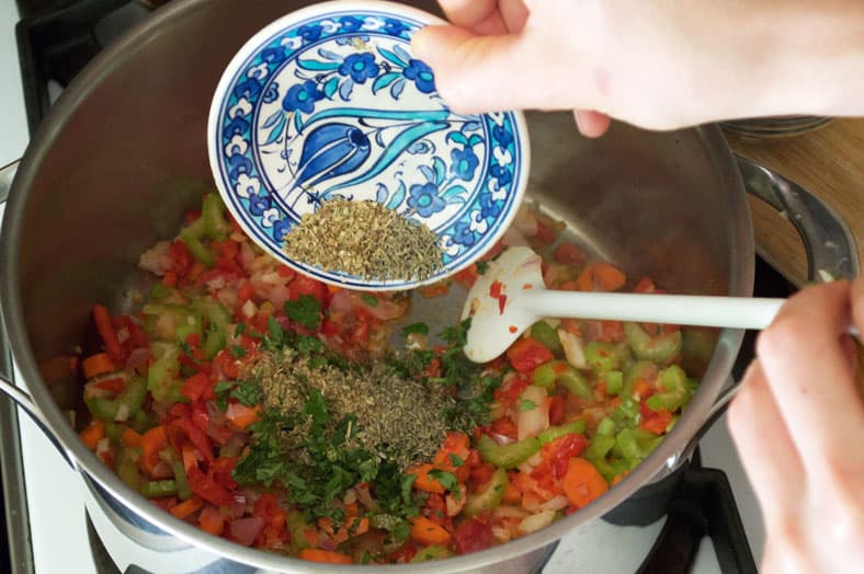 To make Moro de Guandules, a traditional Dominican Pigeon Peas Rice dish, you'll start by sauteeing garlic, onion, red pepper, carrots and celery and then adding your dry herbs