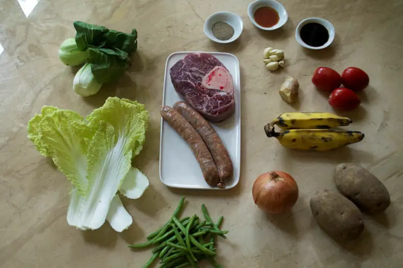Ingredients for Pochero, a Filipino pork stew with baby corn, bok choy, tomatoes, onions, garlic, ginger, green beans and chorizo