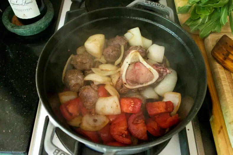 The half-way point of making Pochero, a Filipino pork stew, with the beef stewing with tomatoes, onions, garlic and ginger