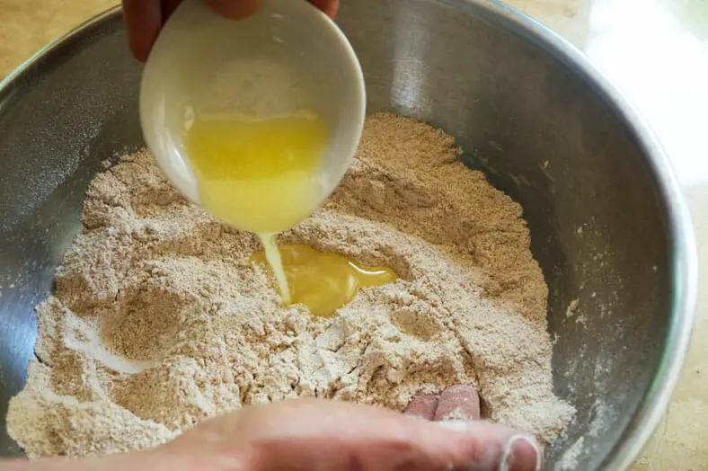 Adding melted butter to whole wheat pastry flour, cinnamon, coconut sugar, cardamom, and salt to make Kenyan Cardamom Beignets or Doughnut
