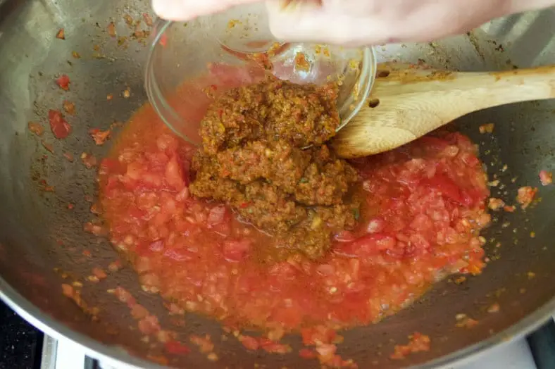 To make Puerto Rican Mamposteao, you start by adding crushed tomotoes and sofrito into a hot pan so the ingredients and flavors mingle together