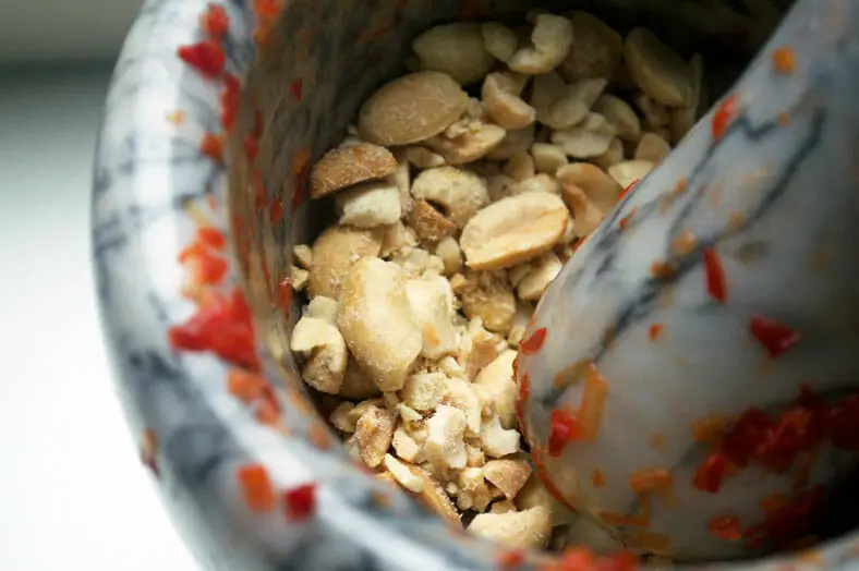 Here we are pounding peanuts in a mortal and pestle for Singapore's signature chili crab dish