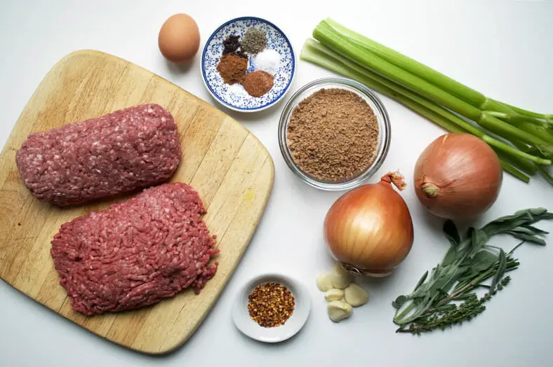 Before the tourtière (Canadian Christmas meat pie) filling is made, you have the raw ingredients. In this recipe, we use ground pork, ground beef, onions, garlic, celery, nutmeg, cinnamon powder, allspice, cloves, sage, thyme, and breadcrumbs as a thickener