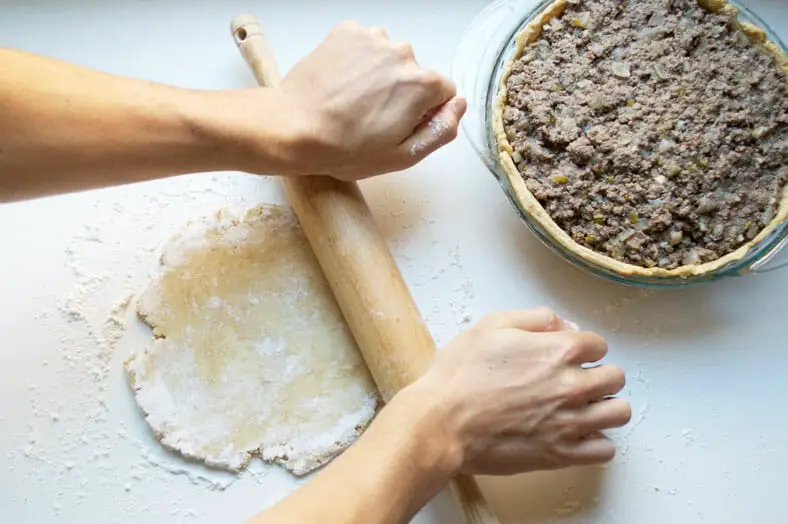 As with any pie crust, roll it out as flat as you can so it can cover the full baking dish. You want the filling of your tourtière (Canadian Christmas spiced meat pie) to steam in between the pie crusts!