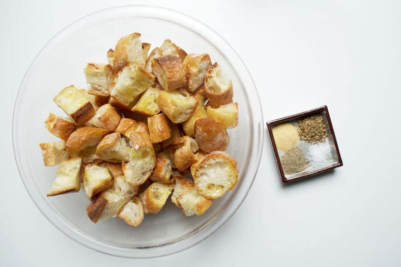 The make Cesnecka, the ever popular Czech Garlic Soup, you'll want to start by cutting up a baguette and making some croutons coated in olive oil, garlic powder, pepper, salt and oregano that will top the soup.