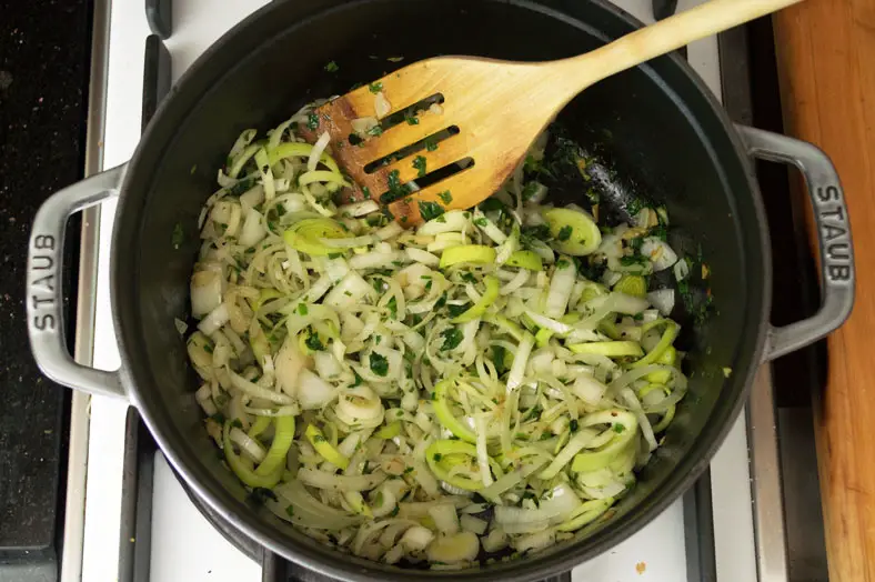 As your onions start to sweat and soften, add in your sliced leek into the pot as well